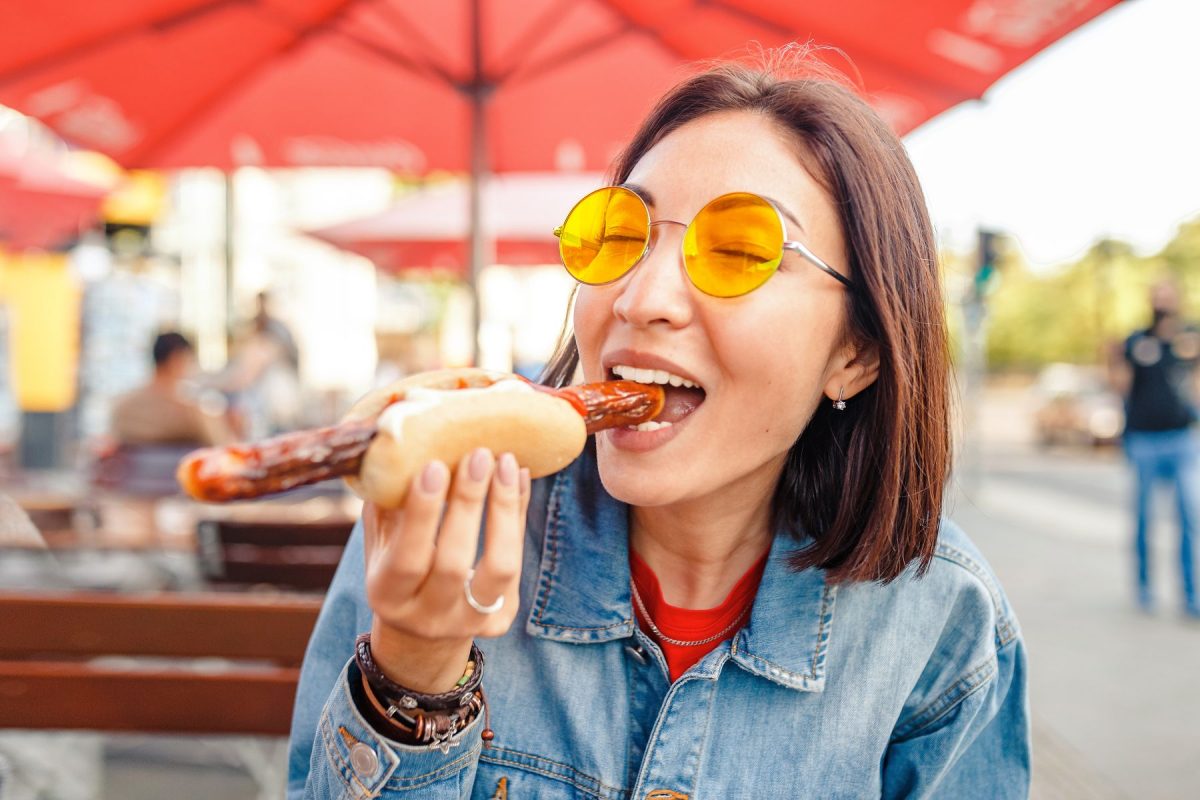 woman eating sausage on a bun at festival